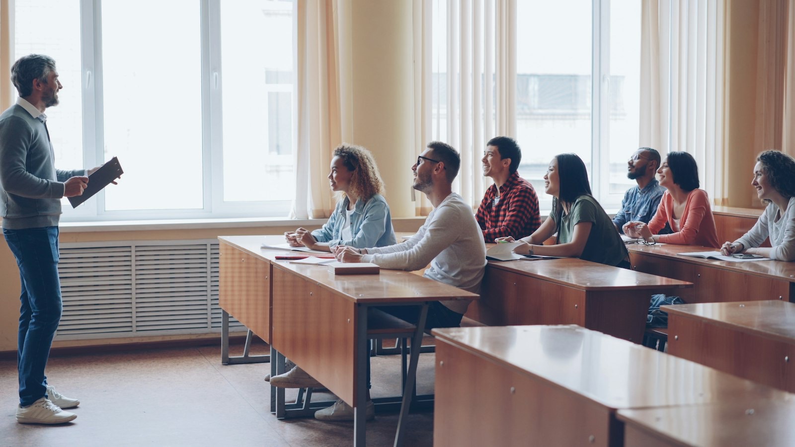 An instructor lecturing to students in a bright classroom.